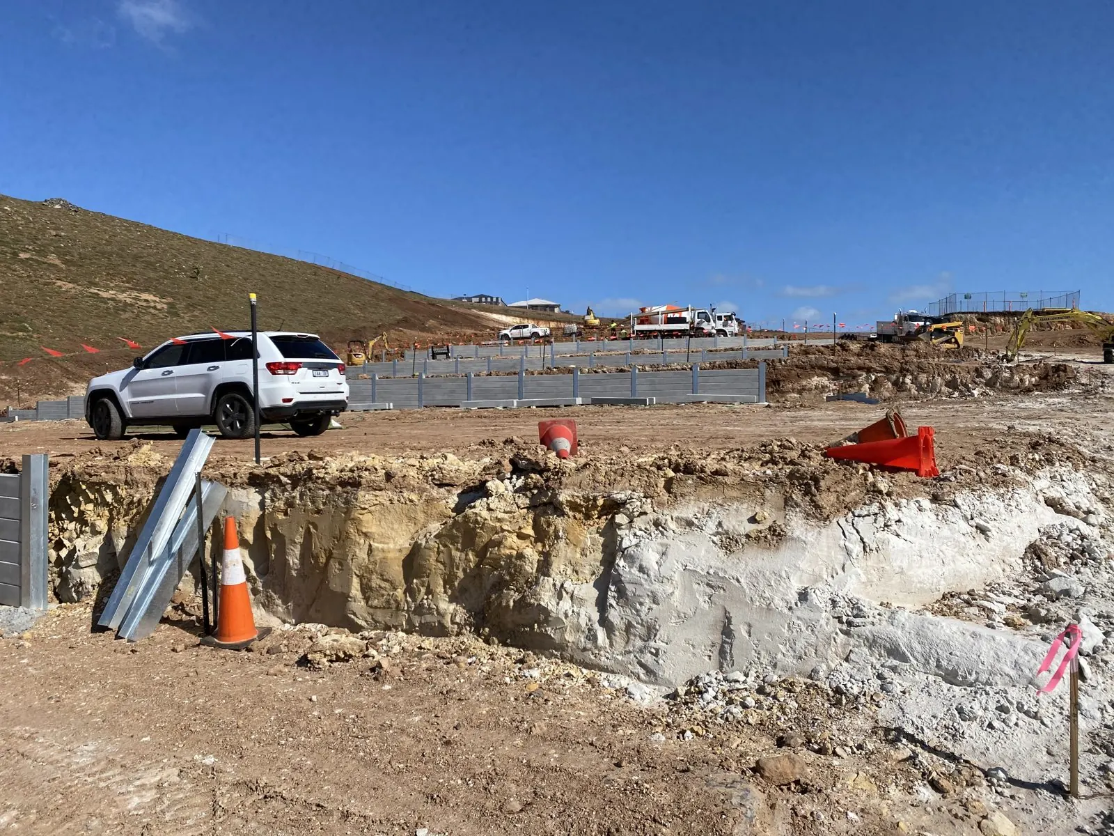 Excavated ground and concrete sleeper retaining walls across a sloping construction site